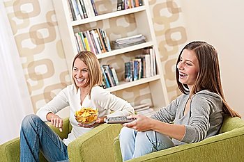 Students - Two smiling female teenager watching television in modern living room