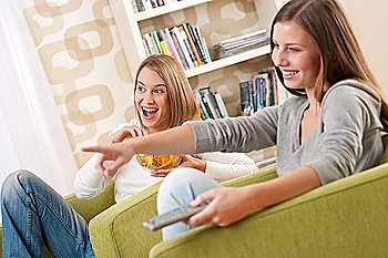 Students - Two smiling female teenager watching television in modern living room
