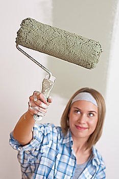 Home improvement: Smiling woman with paint roller painting wall