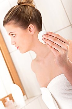 Young woman cleaning her face, focus on cotton pad in the hand
