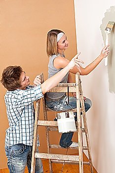 Home improvement: Young couple painting wall with paint brush