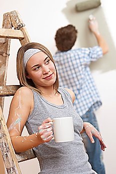 Home improvement: Young couple painting wall with paint roller