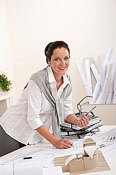 Smiling female architect with plans at the office holding glasses