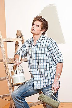 Home improvement: Young man with paint roller, paint can and ladder