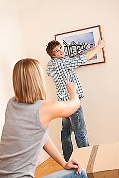 Moving house: Couple hanging picture on wall in new home