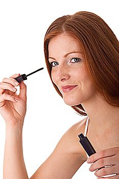 Smiling red hair woman applying mascara on white background