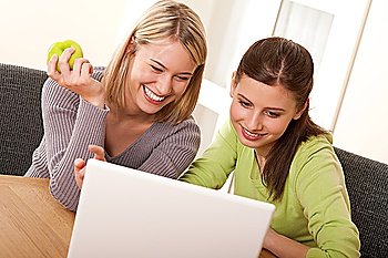Two smiling teenage students having fun with laptop