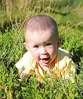 happy smiling baby crawling in green grass