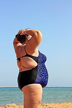 overweight woman standing on beach with hands up