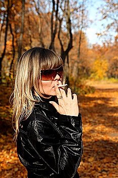 beautiful young girl with cigarette in autumn park