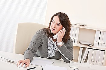 Smiling young business woman working on the phone at office