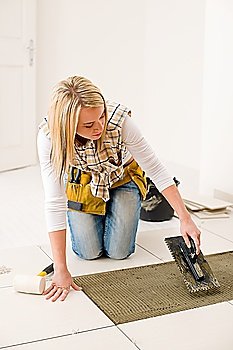 Home improvement, renovation - handywoman laying tile, trowel with mortar