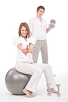 Young healthy couple training with weights and fitness ball on white