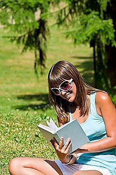 Happy young woman with book in park on sunny day