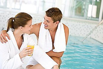 Young happy couple relax at swimming pool, drink juice