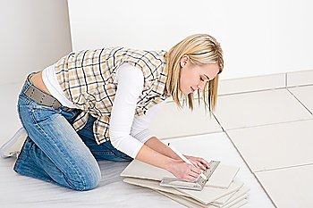 Home improvement - handywoman measuring tile, focus on ruler