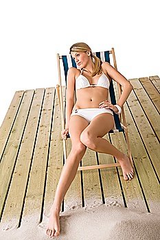 Beach - Woman in white bikini sunbathing on deck chair with sand