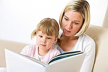 Mother with little girl read book together in lounge