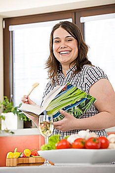 Cook - Plus size happy woman holding cookbook in kitchen