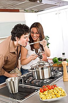 Couple cook in modern kitchen - man taste food