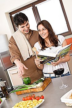 Smiling couple in modern kitchen cook together with cookbook