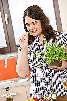 Cook - plus size woman with herb and vegetable in modern kitchen