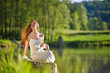 Long red hair romantic woman relax by lake on sunny day