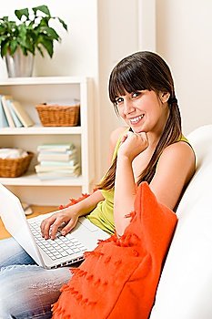 Teenager girl relax home - happy with laptop sitting on sofa