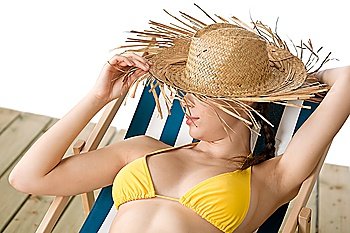 Beach - woman with straw hat in yellow bikini relaxing