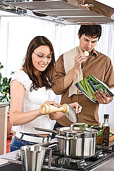 Happy couple cook together in modern kitchen with cookbook