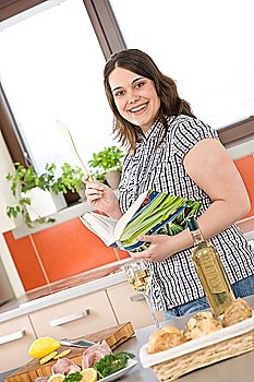 Cook - plus size woman prepare fish with white wine and bread in modern kitchen holding cookbook