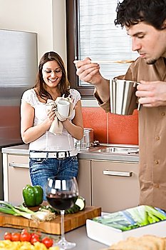 Happy couple cook together in modern kitchen, man tasting