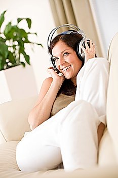Smiling woman with headphones listen to music, plant in background