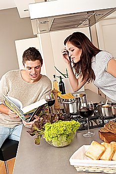 Young couple cooking in kitchen together with cookbook