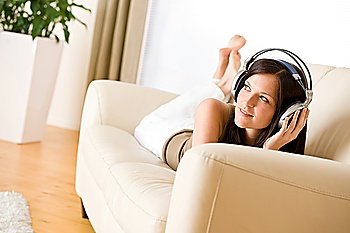 Woman with headphones listen to music in lounge, plant in background
