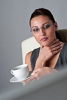 Successful business woman at office having cup of coffee sitting at computer desk