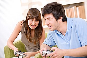 Student - happy teenagers playing video game with control pad in living room