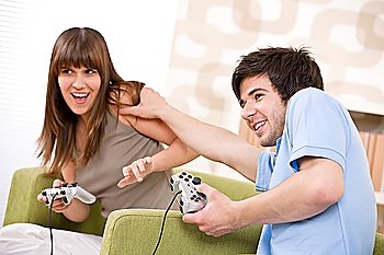 Student - happy teenagers playing video game with control pad in living room