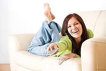 Cheerful woman switch television in living room with remote control