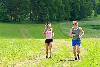 Young fit couple jogging on summer day in meadows countryside