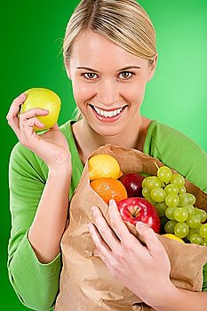 Healthy lifestyle - woman with fruit shopping paper bag on green background