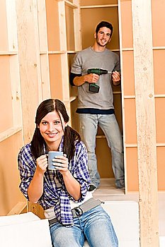 Home improvement smiling young couple fixing wall with hand drill