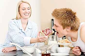 Breakfast happy couple  man feed toast to woman in kitchen