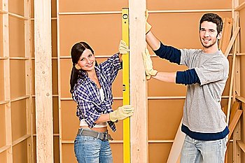 Home improvement smiling young couple fixing wall with spirit level