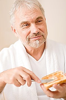 Senior mature man having breakfast butter toast wear bathrobe