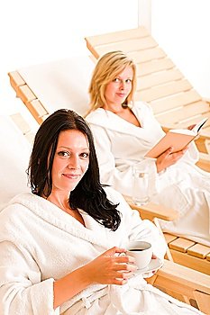 Beauty health spa treatment two women relax sun-beds coffee book