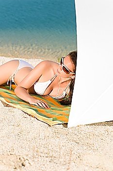 Young sexy bikini model relaxing with sunglasses on beach copyspace