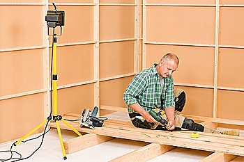 Mature handyman home improvement installing wooden floor in new house
