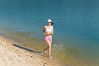 Summer active woman jogging on beach seashore in fitness outfit