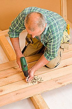 Home improvement - mature handyman fixing new wooden floor with screwdriver